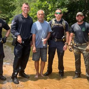 Four police officers posed with the missing man, standing in water.