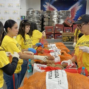 Volunteers at a long table loaded with sacks of potatoes