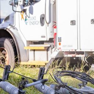 A Duke Energy truck next to power lines/equipment on the ground.