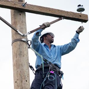 A person high on on an electrical pole making repairs.