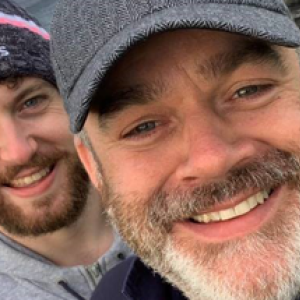 Noel with his partner, both in sweatshirts and hats