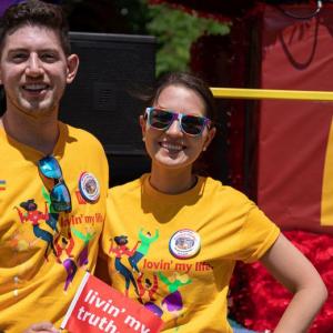 Two people in matching shirts. McDonalds logo and part of a rainbow behind them.