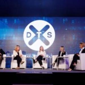 Five people seated on a stage. DTS logo displayed behind them.
