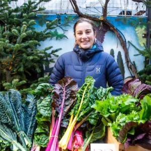 A person behind a table full of fresh produce