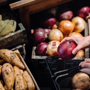 A person holding produce to put in a basket.