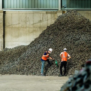 Two workers next to a pile of material
