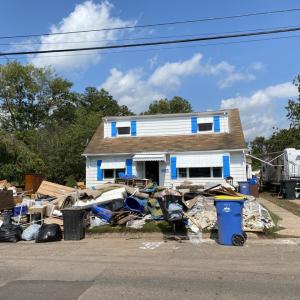 Storm damage to a home, trash from the damage piled up in front of the home.