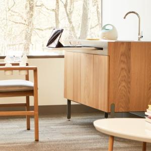 a room with a large window, specialized nursing chair, sink and coffee table.