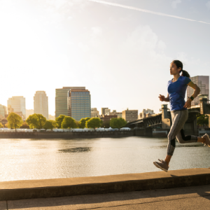 Woman running in front of cityscape at sunrise