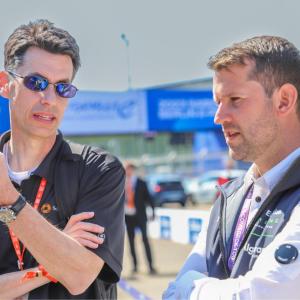 Two people talking on a race track.