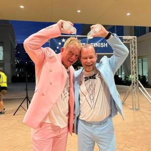 two men in pastel tuxedos pouring water on their heads