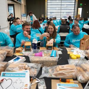 People in turquoise shirts making birdhouses