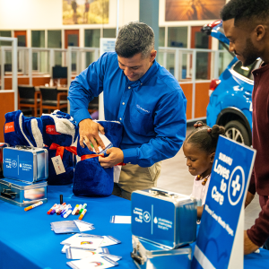 Two adults and a child at a "Subaru Loves to Care" table