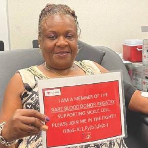 a person donating blood holding a sign "I'm registered as a rare blood donor"