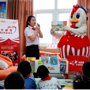 person in chicken costume reading to group of kids
