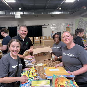 Smiling Wesco Cares volunteers packing children's books
