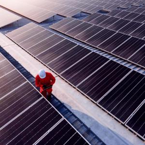 Worker in a hard hat next to solar panels