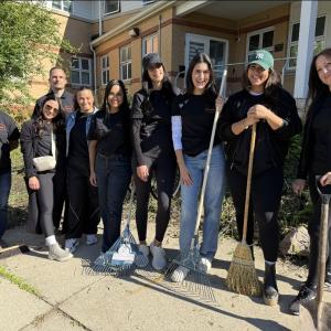 A group standing together outside a building with gardening and cleaning tools