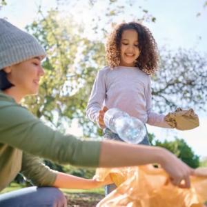Two adults and a child collecting trash in a park setting.