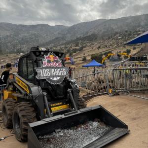 A small construction vehicle on dirt terrain. "Red Bull Los Andes" sign on the front.