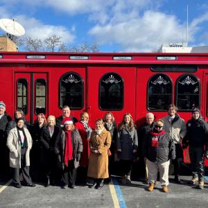 A group posed in front of a red trolley.