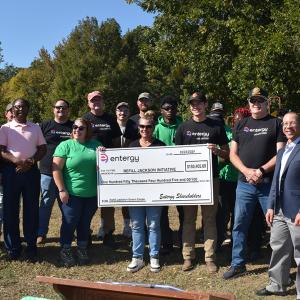 A group posed outside, some holding a large check.