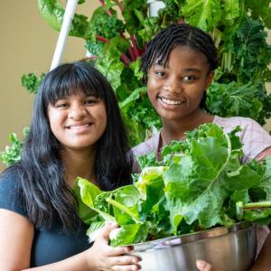 Two young people holding a bowl of greens