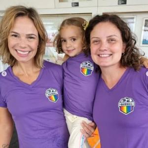 Renata (R), her partner Caru and their daughter Bia, wearing their Rainball team shirts.