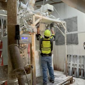 A person in protective gear in a manufacturing area, performing a repair.