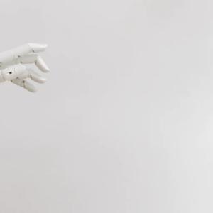 a white robotic hand from the left side of the screen, a white backdrop