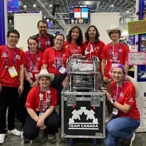 Team in matching shirts next to cases marked "Team Canada" at a robotics event.