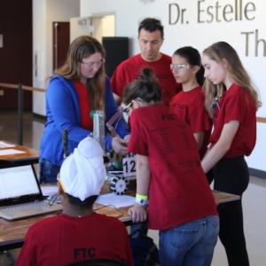 A group of youth and adults working on a robot.