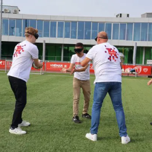 Blindfolded people throwing a ball to each other on a field