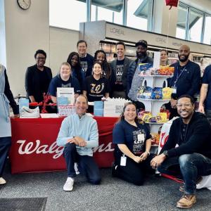 A group of people posed inside a Walgreens by a decorated table with treats and pamphlets.