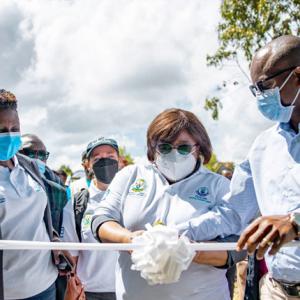 a group of people cut a white ribbon, all wearing medical masks