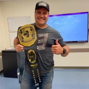 JM Bilodeau posing with a large championship belt over his shoulder.