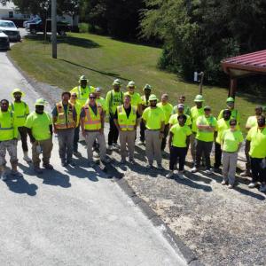 Group of employees posed outside in high-vis vests and hard hats.