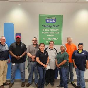 A team posed by a sign "Safety First"