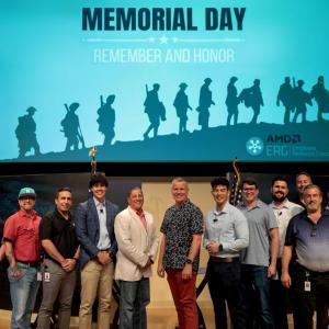 Veterans posing on a stage underneath a large screen that says "Memorial Day - Remember and Honor"