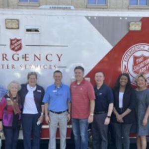 A row of people posed in front of a trailer with salvation army signs.