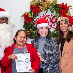 A recipient posed with Santa and Entergy employees.