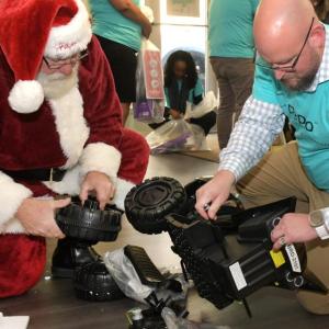 Volunteer helping santa assemble a toy.