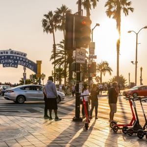 sunset over santa monica yacht harbor. Traffic and pedestrians and a row of rentable scooters