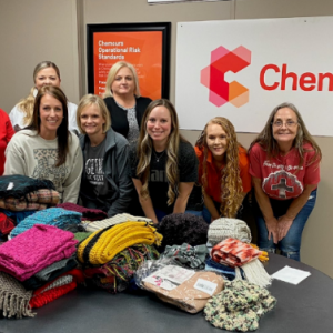 A group of volunteers behind a table full of handmade scarves.