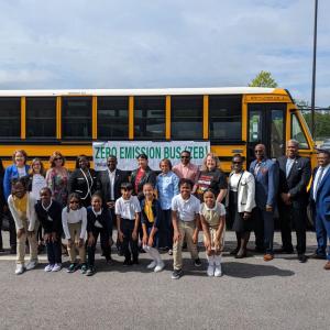 Grantee staff with school officials beside an electric school bus in Clayton County, Georgia