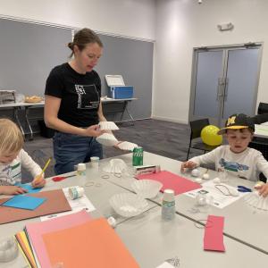 two children and an adult participating in activities at a table