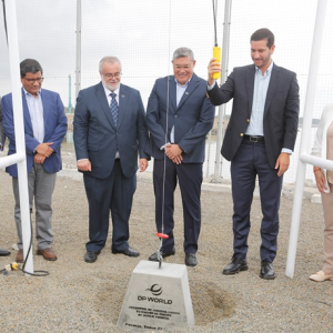 Six people smiling and gathered around a weight on a cable as one lowers it into the ground