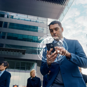 A person outside tall buildings using a cell phone.