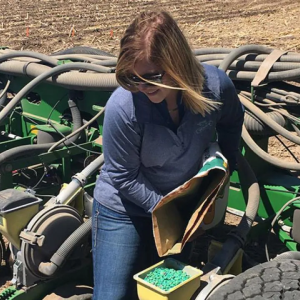 A person loading seed hoppers on a large agricultural machine