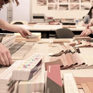 people selecting swatches from a table full of different texture, color, material samples.